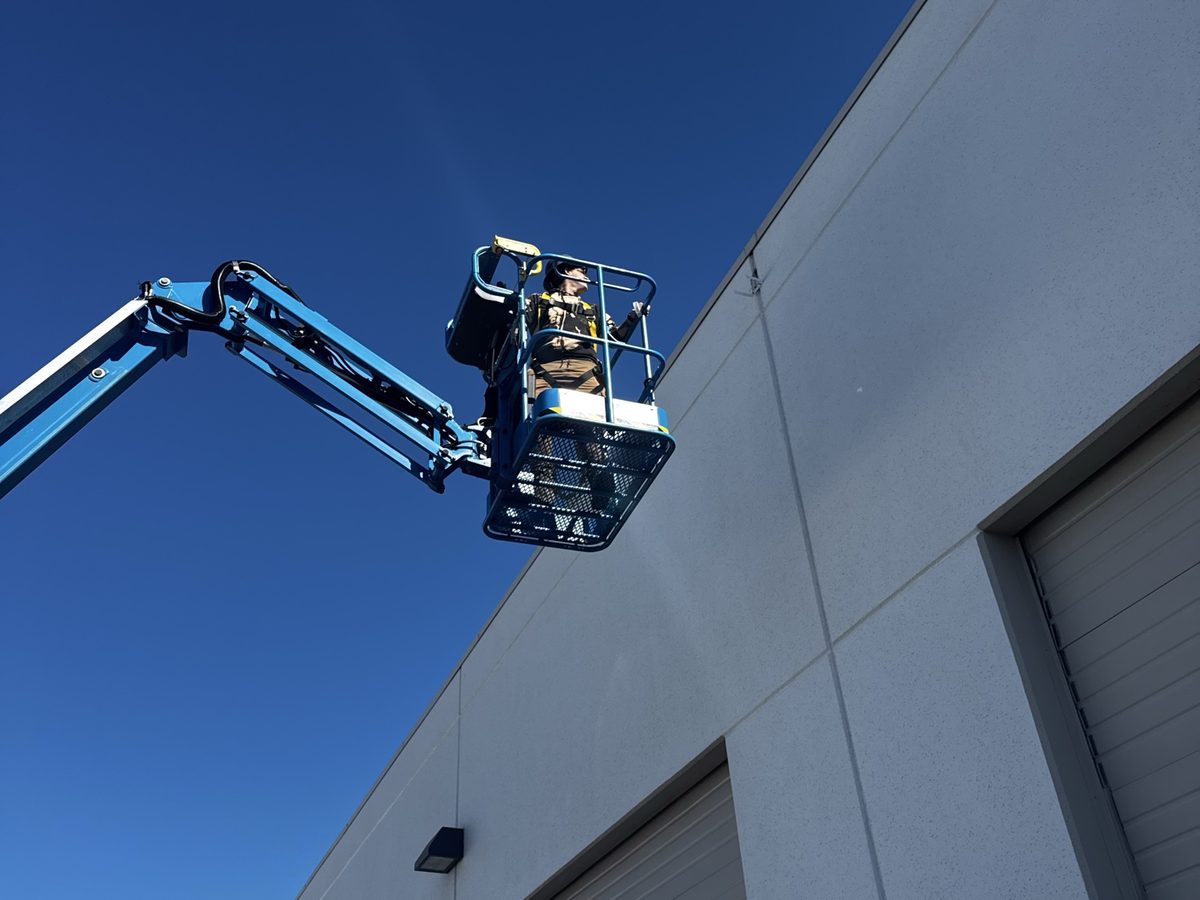 Technician in a boom lift basket working at height on a commercial building exterior