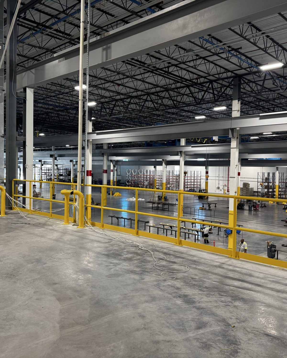 Crew members on a mezzanine overlooking the warehouse floor on a large-scale jobsite